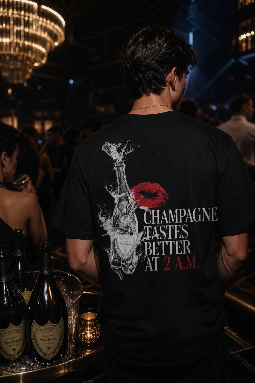 Man wearing the Nocte Champagne Tastes Better at 2 A.M. tee in a candlelit club